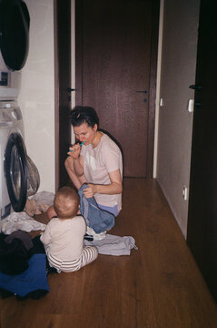 Mother and Child Doing Laundry at Home. Everyday Parenthood On Film