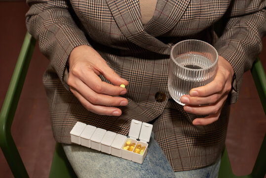 Person taking medication with a glass of water 
