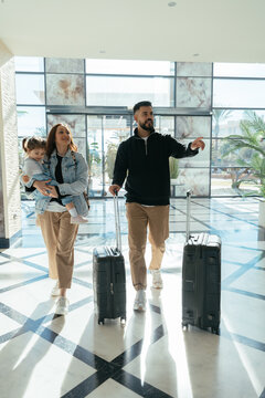 Family arriving at hotel lobby beginning vacation with luggage