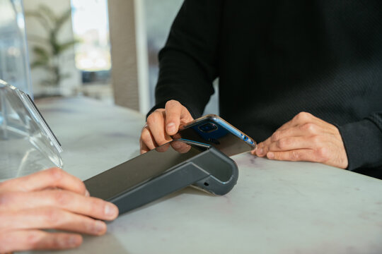 Customer paying with smartphone at hotel reception desk