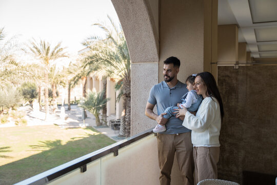 Family enjoying vacation at luxury hotel, admiring view from balcony