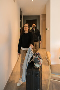 Couple entering hotel room carrying luggage after check-in