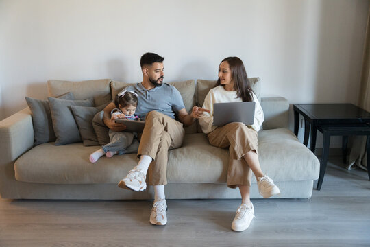 Family relaxing on sofa using electronic devices