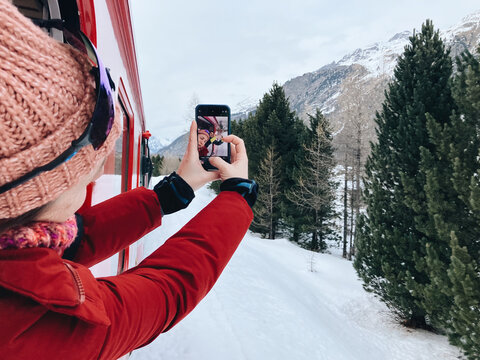 Woman takes a selfie with phone out of train's window