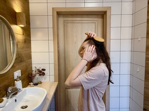 Teenage girl combing her hair in the bathtub