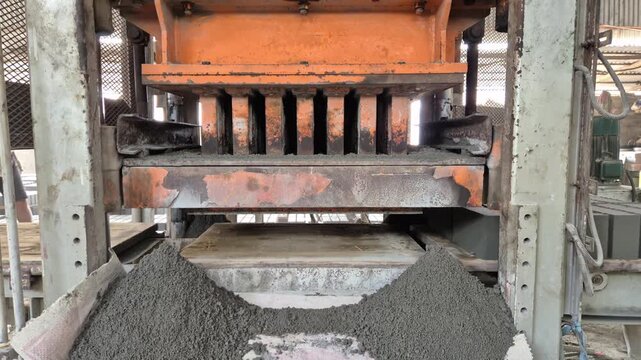 Professional RAW eye level close-up shot of a hydraulic press machine molding cement and sand bricks in Bangladesh, 4K UHD 30fps.
