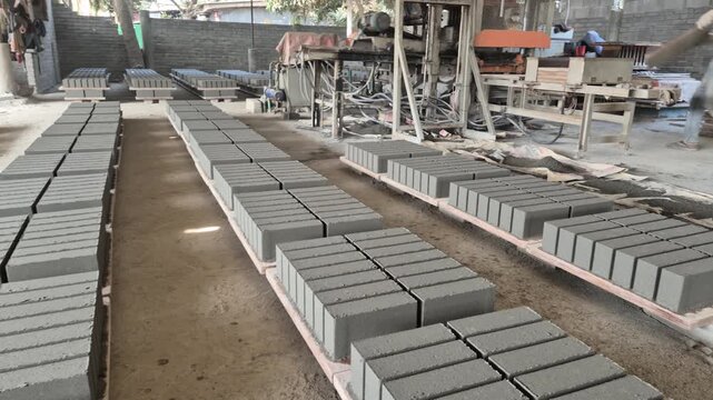 Professional RAW eye level wide shot of sun-dried cured eco-bricks on pallets in a factory in Bangladesh, 4K UHD 30fps.