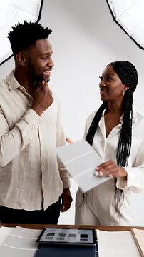 Two creative professionals collaborate discussing color swatches and a digital tablet in a brightly lit studio with