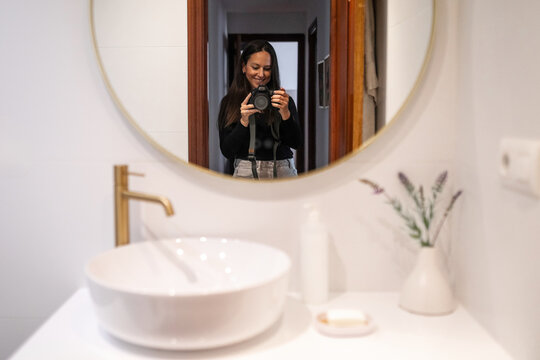 Photographer taking a selfie in her bathroom at home
