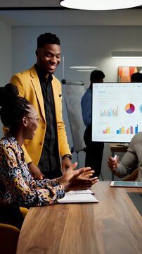 African American Business Professionals Collaborating In A Modern Office During A Meeting With Data Charts On A Screen