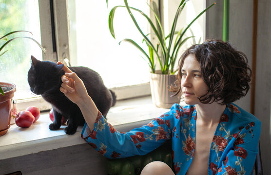 woman petting cat by window