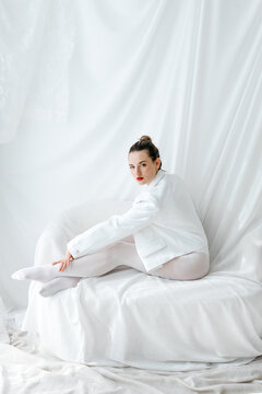 Fashion model posing on white sofa in total white look