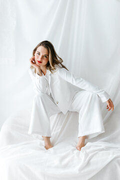 Businesswoman wearing white suit posing on white sheets