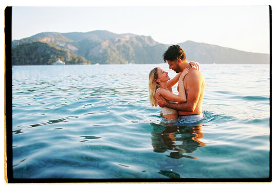 Film photo of happy couple swimming in the sea on vacation at sunset