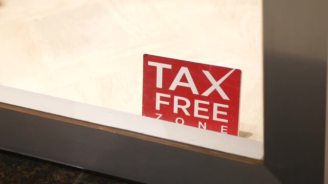 A close-up view of a tax free zone sign in red and white on a glass window, indicating an area where goods or services are exempt from taxes, a still cinematic shot