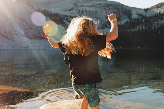 Boy jumpin in front of an alpine lake at sunset