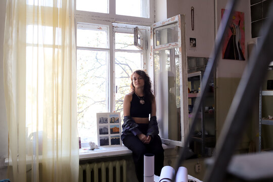 A woman sits on a windowsill in the studio.