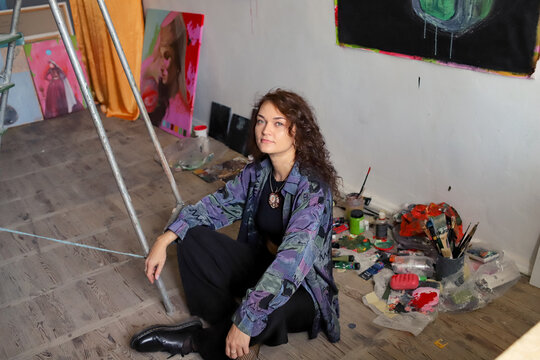 female artist in her studio with paintings