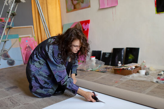 female artist cutting paper in studio