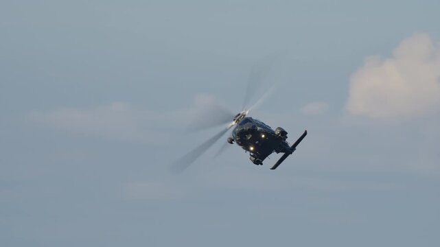 LUQA, MALTA - SEPTEMBER 28, 2025: Video footage of a dark gray military helicopter flying. The clip begins with a head-on approach, then pans to a side profile view as it flies past, and ends with it