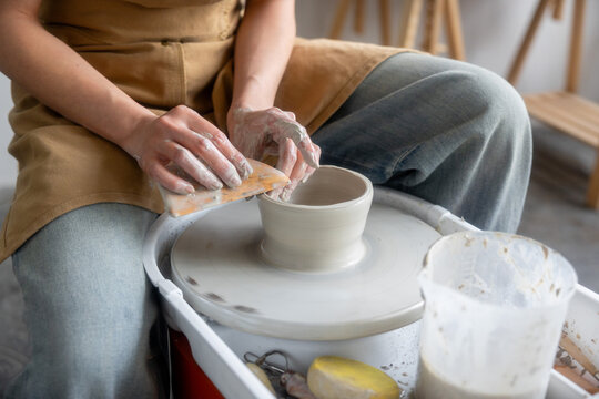 ceramic artist working on the wheel with a spatula