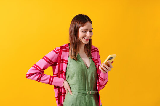 Smiling Woman Checking Phone against a vibrant yellow background