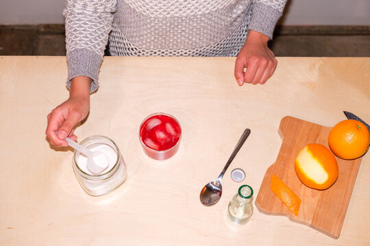 woman making mocktail drink with electrolyte powder 
