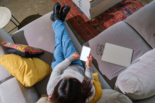 Top down woman on couch holding phone