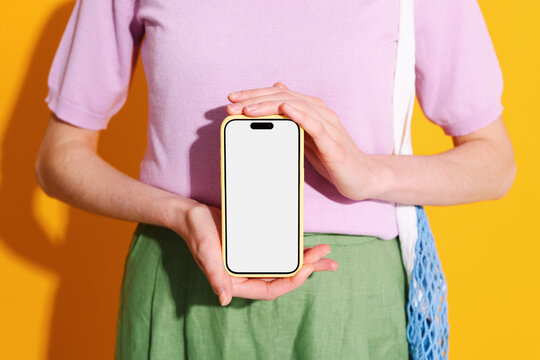 Mockup phone with white screen.  A woman holds phone on yellow