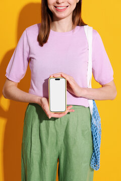 Mockup phone with white screen.  A woman holds phone on yellow