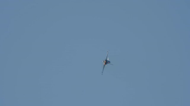 LUQA, MALTA - SEPTEMBER 28, 2025: A Eurofighter Typhoon fighter jet with afterburners blazing performs incredible high-speed aerobatic maneuvers, rolling and turning against a clear, solid blue sky