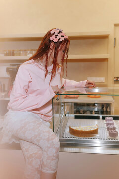 Woman in pink outfit leaning on bakery display case