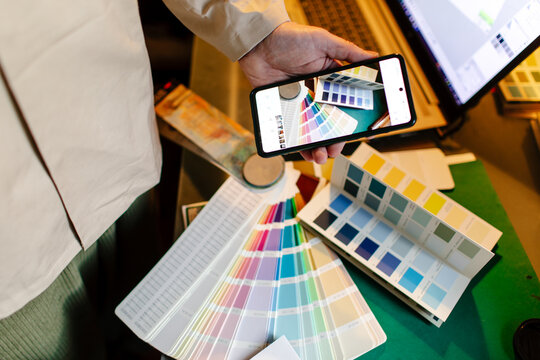 
hands of a designer photographing layouts with color