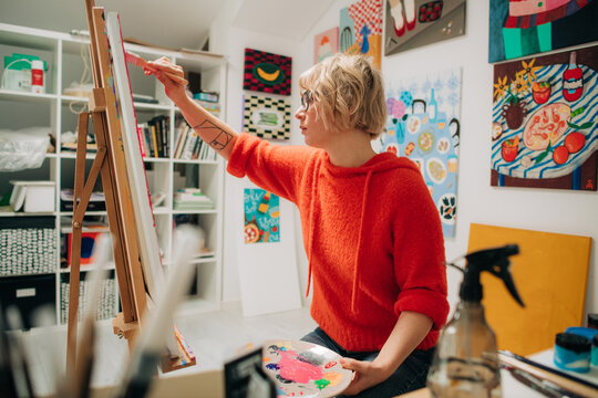 Female artist painting on canvas in home studio