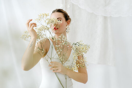 Woman posing with delicate white flowers, embracing purity