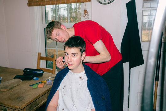 older bother giving his younger sibling a haircut 