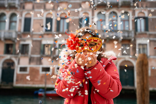 Child with mask throws confetti. Venice carnival, Italy