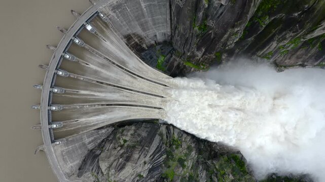 Aerial view of extreme spillway release at Aldead&aacute;vila Dam, Spain. Massive floodgates discharge over the Douro River canyon, creating mist and dramatic hydroelectric power scene in Arribes del Duero.
