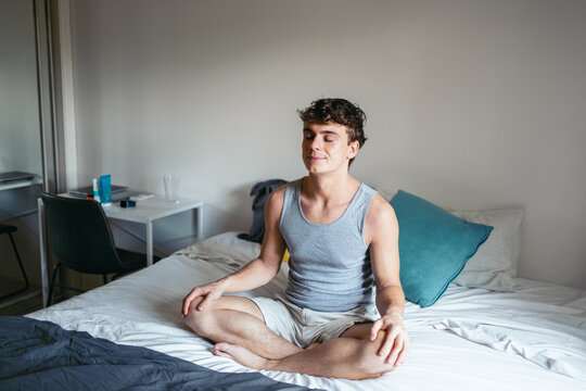 Cheerful man meditating in the morning on the bed