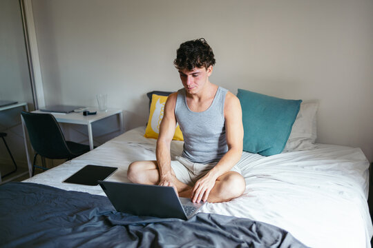 Young man working with laptop in bed