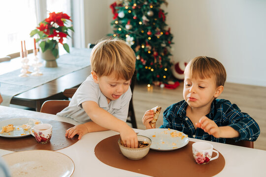 Toddler stealing food from his brother's plate