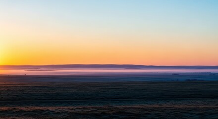 Fototapeta premium The tranquil moment of early morning light breaking over a vast landscape, illuminating the mist and painting the horizon with soft colors, haze, serenity, wide