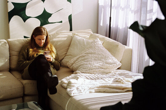 Woman immersed in social media on a cozy couch in Australia