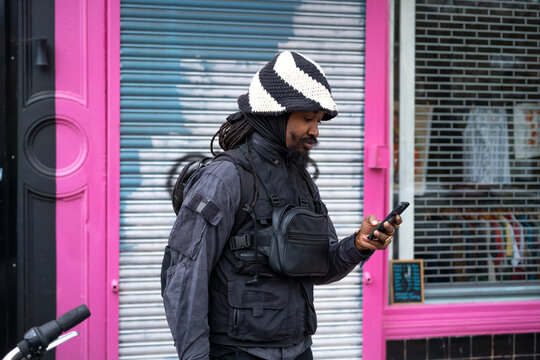 Black man texting by vintage shop