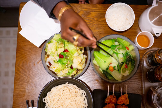 Black mans hand eating with chopsticks