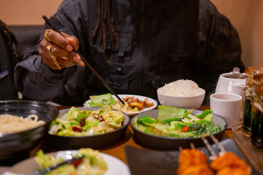 Black man eating Chinese food with chopsticks
