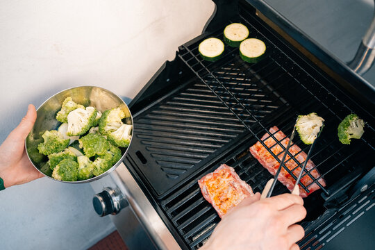 Grilling broccoli and meat on outdoor barbecue grill