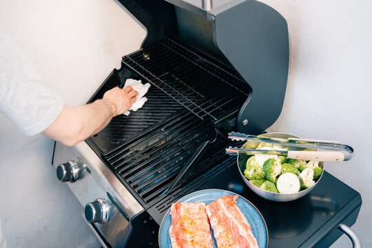  Person cleans grill with paper towel before cooking