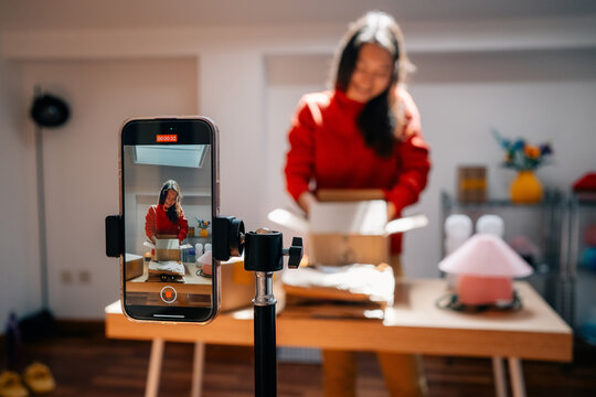 A person records video while opening package on smartphone tripod