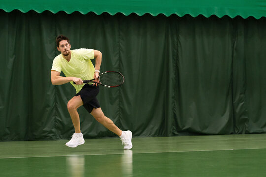 Tennis Player Running to Hit the Ball in Indoor Court
